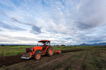 agricultural man working with plowing tractor in the beautiful farmland, Mae Sot, Tak, Thailand