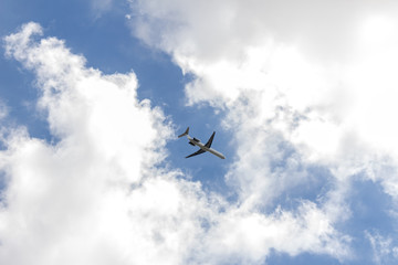 Fototapeta na wymiar Airplane on a blue sky with soft white clouds.