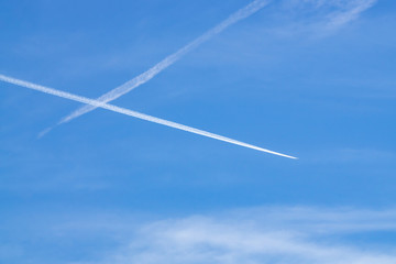The contrails of two planes crossing over the blue sky