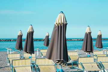 Obraz premium Italian summer on the Adriatic Sea: tyipical italian Riviera Romagnola beach clubs with sunbeds and beach umbrellas with typical vintage colors and look