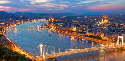 Fototapeta premium Aerial view of Budapest, Hungary with clouds. Buda castle, Chain bridge and Parliament building at sunset with lights on