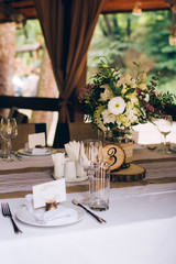 Beautiful decorated elegant wedding table for dinner with floral white bouquets, candlesticks and a white tablecloth glasses and porcelain plates