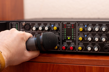 microphone in hand and audio amplifier. sound engineer vocal recording. mixer