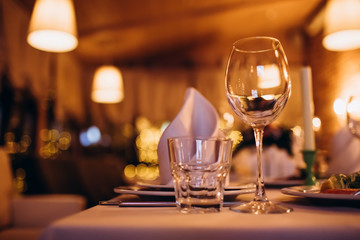 Beautiful decorated elegant wedding table for dinner with floral white bouquets, candlesticks and a white tablecloth glasses and porcelain plates