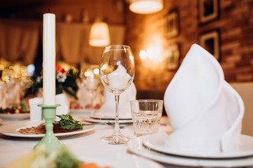 Beautiful decorated elegant wedding table for dinner with floral white bouquets, candlesticks and a white tablecloth glasses and porcelain plates