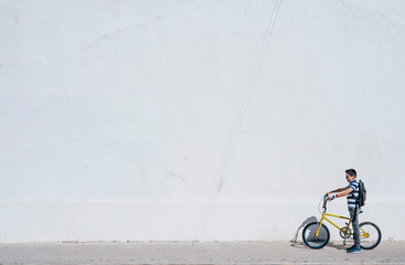 Cute little boy is riding a bike. A concrete white wall background