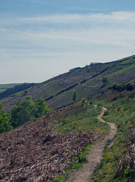a narrow walking path on high moorland surrounded by pasture with stone walls above crimsworth dean valley in west yorkshire
