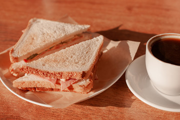 breakfast table with sandwich and black coffee