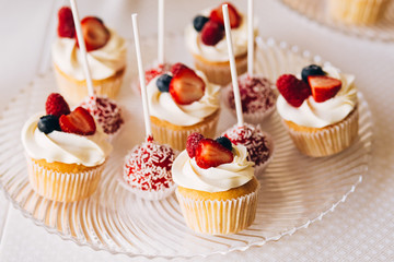 Beautiful cake covered with icing cream, summer berries on the top. Style and food photography