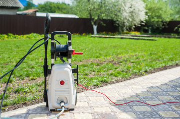 White pressure portable washer front view on the garden near the garage