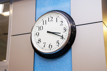 Round chrome clock with white dial on the office wall