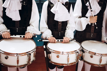 A closeup of the hands of a drummer at a parade. Children's ensemble in white shirts. White new...