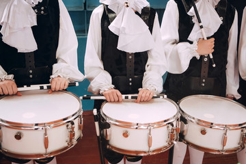 Obraz premium A closeup of the hands of a drummer at a parade. Children's ensemble in white shirts. White new snare drum, white sticks. The concept of a military parade and march.