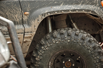Wheels, lights and bumper are laced in a swamp. Dirty truck parts close up.