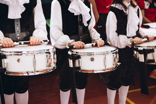 A closeup of the hands of a drummer at a parade. Children's ensemble in white shirts. White new snare drum, white sticks. The concept of a military parade and march.