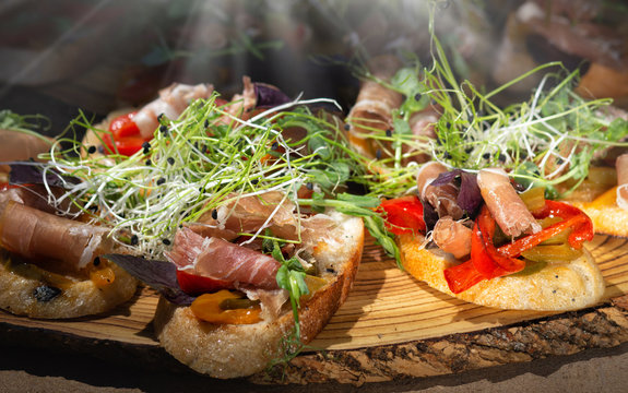 Close up bruschetta with proschuto, tomato, parmesan cheese and arugula