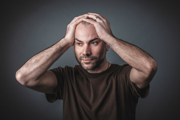 Studio portrait of pensive man with his hands holding his head.