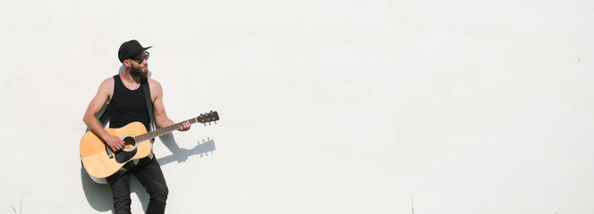 Guitar player outside over white wall