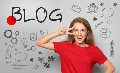 Portrait of beautiful young woman showing victory gesture on light background