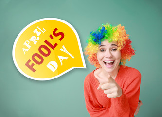 Funny woman with wig for April Fools' Day celebration on color background