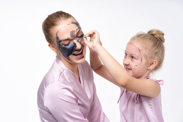 young mothers and young daughter Europeans conduct facial skin care procedures. Family treatments. Cosmetic skin care.