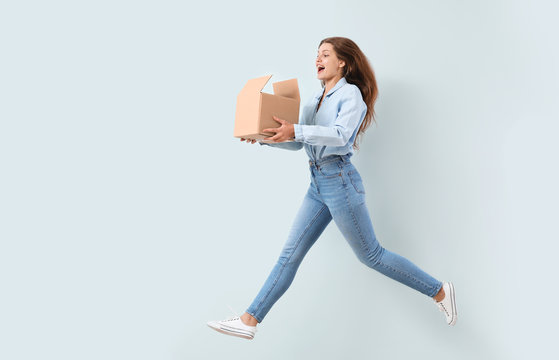 Jumping woman with cardboard box on light background