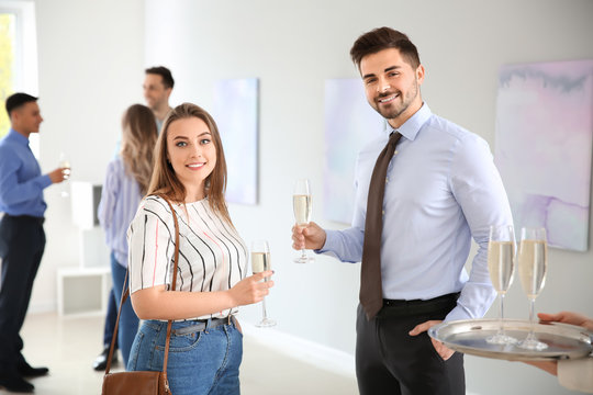 Couple drinking champagne at exhibition in modern art gallery
