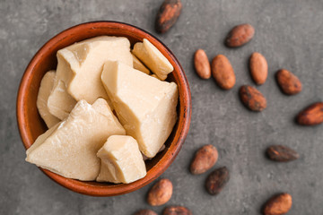 Bowl with cocoa butter on grey background