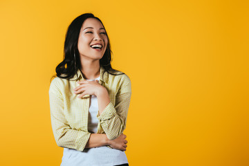 brunette asian girl laughing isolated on yellow