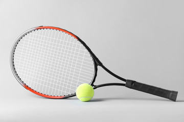 Tennis racket and ball on grey background