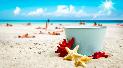 A blue metal bucket with free space for your product. The possibility of mounting bottles with drink, ice cream, food or other products. Blurry beach with people and ocean view.