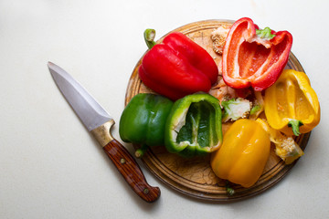 fresh bell peppers on chopping board. knife on side. top angled view.
