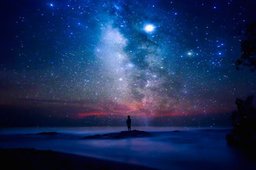 Sternenhimmel über Meer und Strand mit Mannschattenbild. Mann steht am Meeresstrand unter Sternenhimmel.