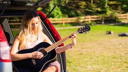 Fototapeta na wymiar Hippie woman playing guitar in van car