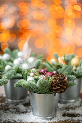 Beautiful festive set. Small arrangements of fresh spruce, pink ornamentals in a rustic wooden box. Christmas mood. Garland bokeh on background. Bokeh of Garland lights on background.