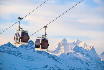 Ski-lift and ski slope in snowy mountains at sunny winter day