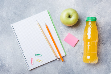 School supplies and Breakfast crackers, orange juice and fresh Apple on the grey table with copy space. concept school.