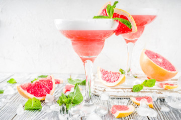 Summer trend alcohol drink. Cold citrus martini cocktail. Aperol spritz, with fresh grapefruit and mint. Wooden white background, copy space