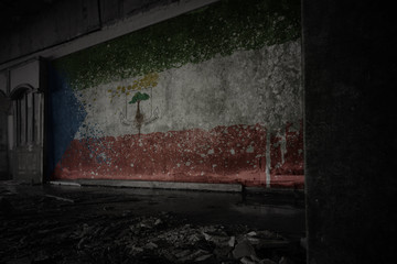 painted flag of equatorial guinea on the dirty old wall in an abandoned ruined house.