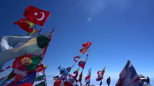 Flags flap gently in the wind in the desert salt flats of Salar de Uyuni in Bolivia, the light breeze in slowmotion moves them magically. On a sunny day with clear bright blue sky