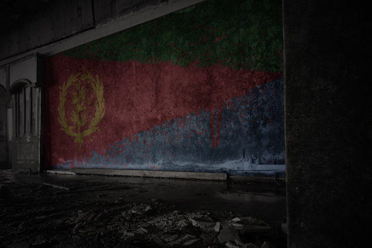 painted flag of eritrea on the dirty old wall in an abandoned ruined house.