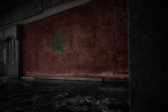 painted flag of morocco on the dirty old wall in an abandoned ruined house.