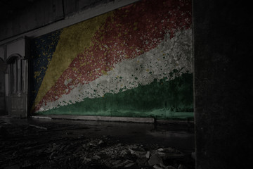 painted flag of seychelles on the dirty old wall in an abandoned ruined house.