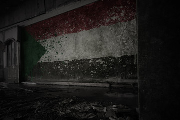 painted flag of sudan on the dirty old wall in an abandoned ruined house.
