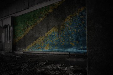 painted flag of tanzania on the dirty old wall in an abandoned ruined house.