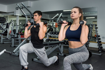 Trainer showing how work with dumbbell to young woman