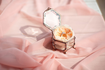 Fototapeta na wymiar Beautiful engagement ring with flower in glass box on table