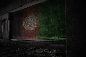 painted flag of afghanistan on the dirty old wall in an abandoned ruined house.