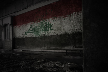 painted flag of iraq on the dirty old wall in an abandoned ruined house.