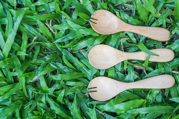 top view of wooden spoon and fork on green grass background